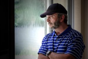 Middle Aged Man Looking Pensively out a Window at Home