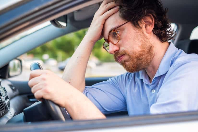 Man Driving In Car While Stressed, His Hand is to His Forehead