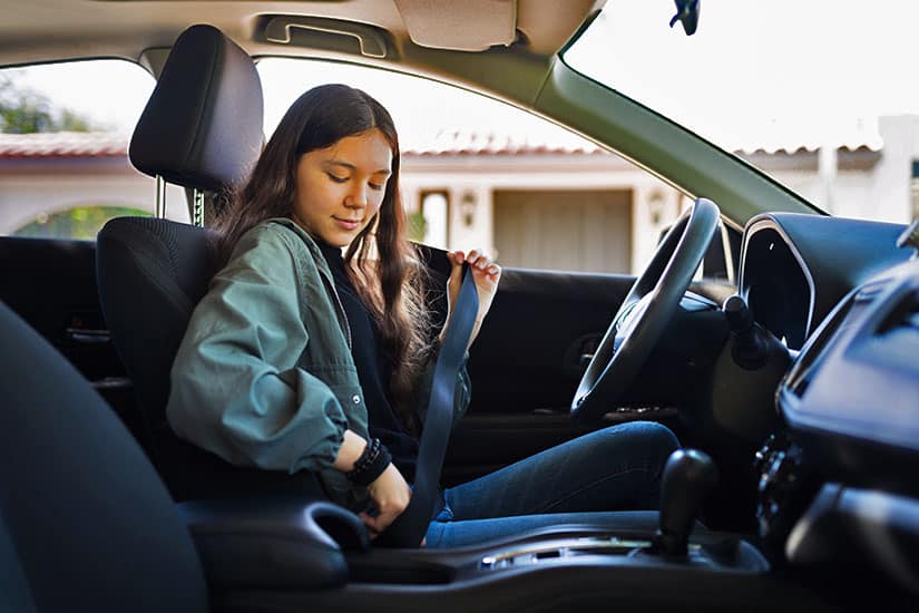 teenage girl putting on seatbelt