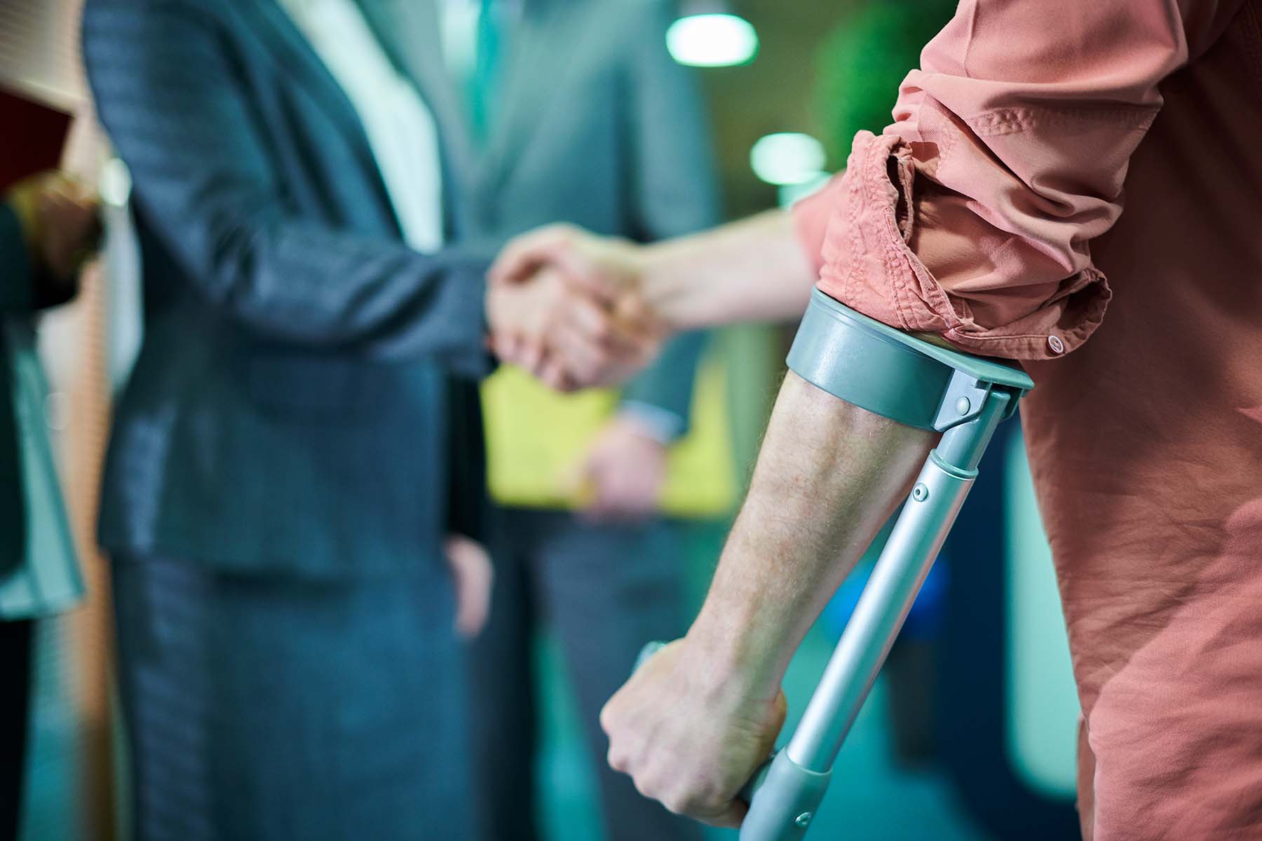 injured man with crutch shaking hands with lawyer