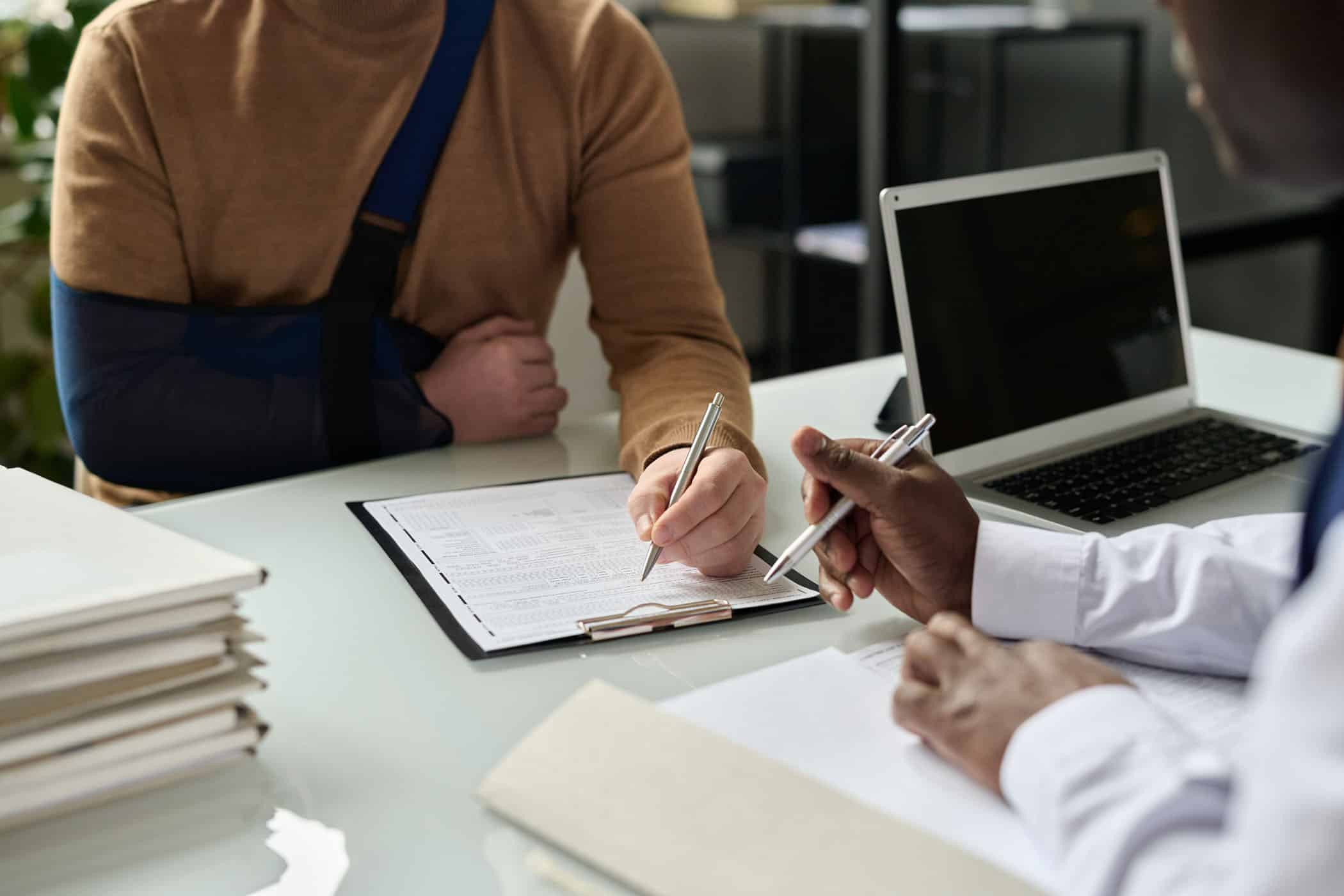 close up of injured man filling in form with attorney